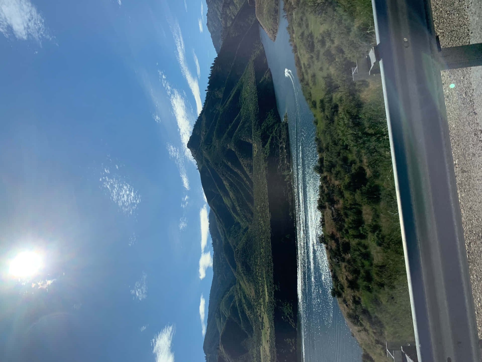 Idaho summer 壁紙 — 從路邊護欄眺望，明亮的陽光下，蜿蜒的河流兩旁是陡峭的青山，藍天白雲。