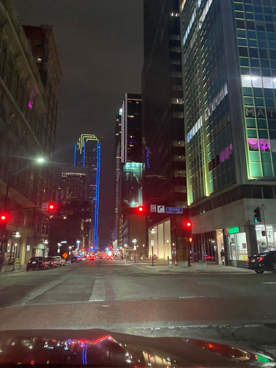dallas 桌布 壁紙 — 從車內觀看的夜間城市街道景觀，發光的摩天大樓和紅色交通燈照亮潮濕的人行道。