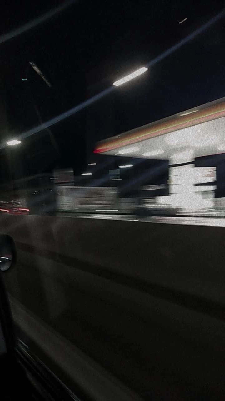 Blurry 桌布 壁紙 — 從車窗看到的夜間動態模糊景象，顯示出燈火通明的加油站和路燈掠過。