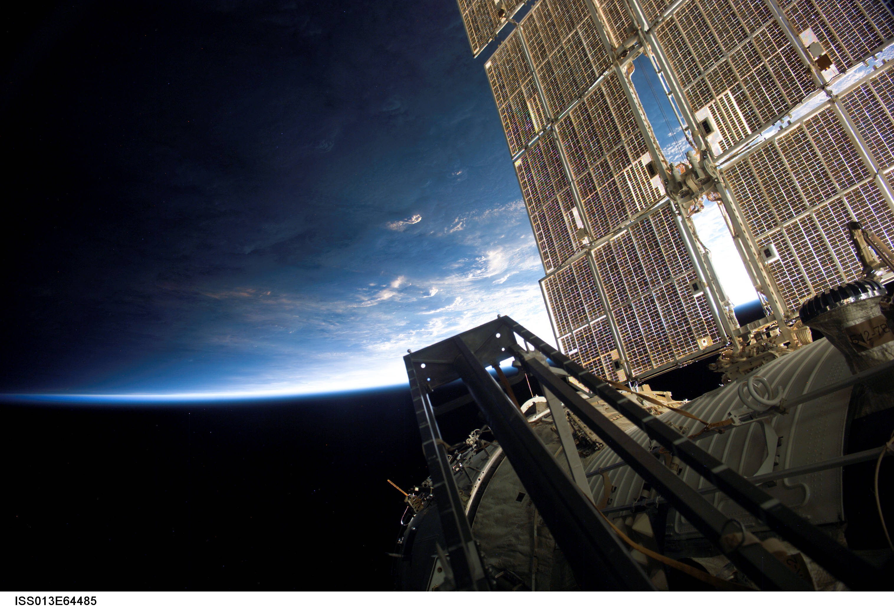 Nasa Aesthetic 桌布 壁紙 — 從軌道上近距離觀察國際太空站的太陽能電池陣列，背景是地球彎曲的藍色和黑色地平線。