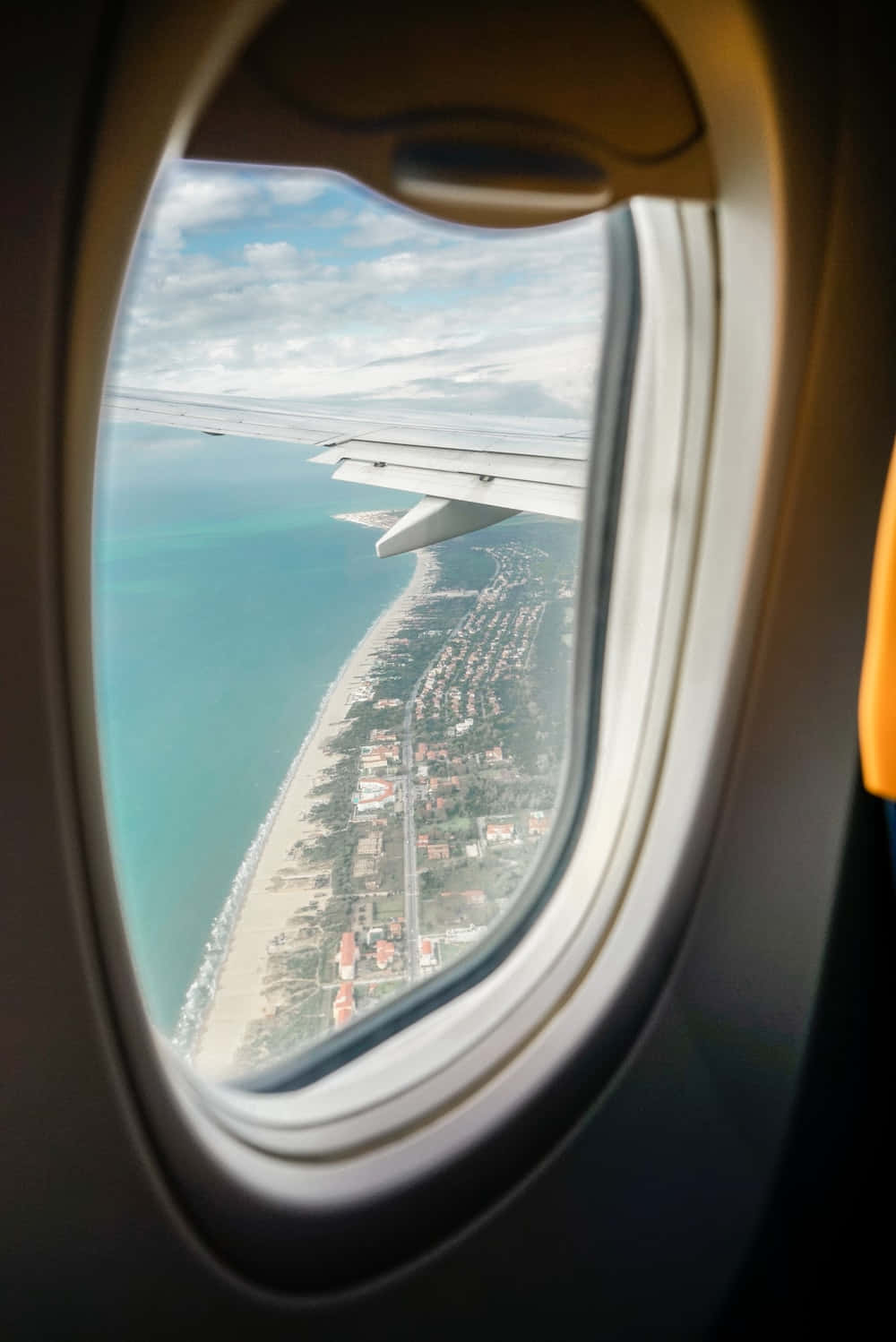 Airplane Window 桌布 壁紙 — 從飛機窗戶俯瞰，機翼下方是碧綠的海洋和沿海小鎮。