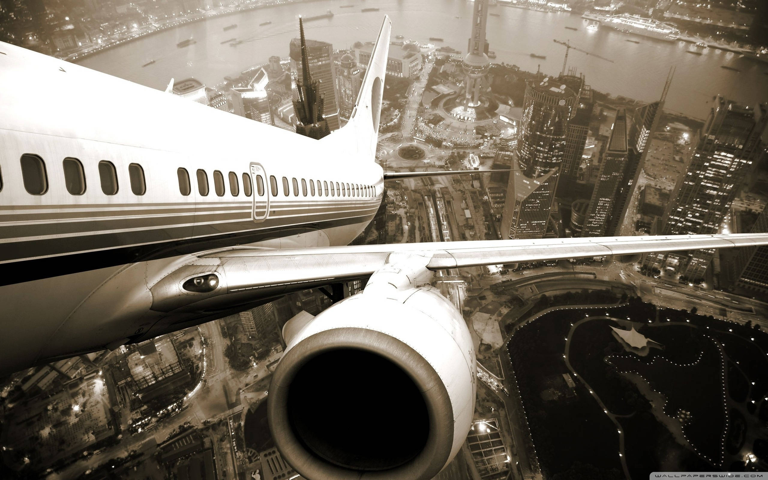 HD Plane 桌布 壁紙 — 從飛機窗戶俯瞰夜間廣闊的燈火通明城市景觀的懷舊色調航空照片。