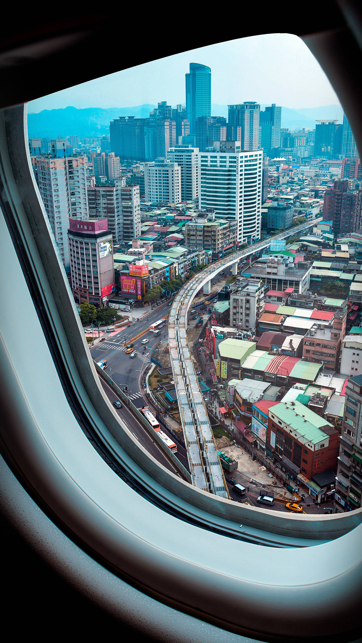 城市風景 桌布 壁紙 — 從飛機窗戶俯瞰密集的城市景觀，蜿蜒的高架道路和色彩繽紛的屋頂盡收眼底。