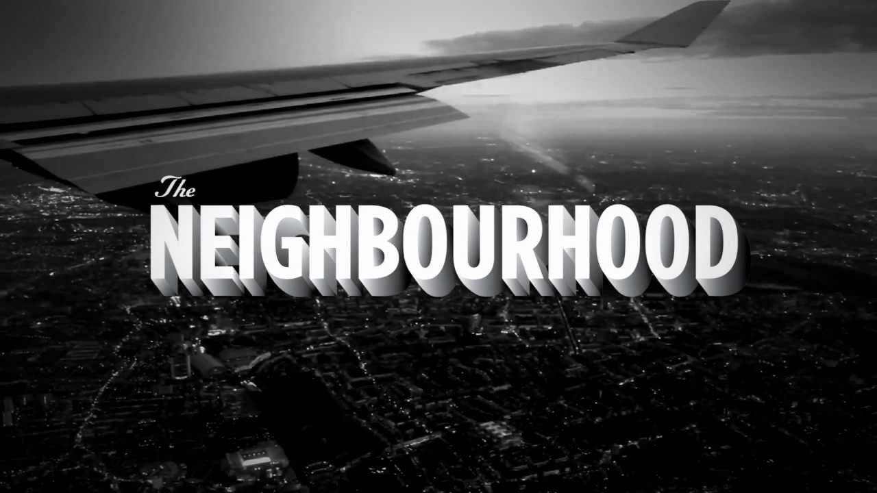 Neighbourhood 桌布 壁紙 — 從飛機窗戶拍攝的黑白鳥瞰圖，展示了機翼下方夜晚燈火通明的街道和建築物，呈現出廣闊的城市景觀。