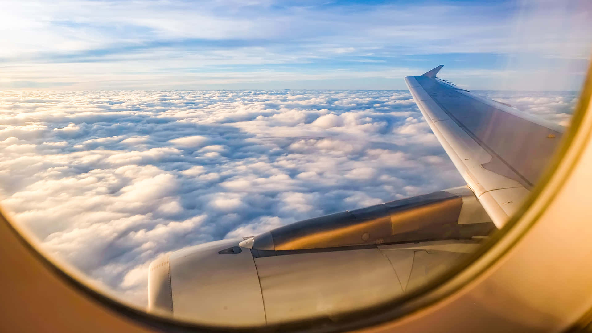 Airplane Window 桌布 壁紙 — 從飛機窗戶看到的機翼和引擎，俯瞰藍天下無盡的蓬鬆白雲。
