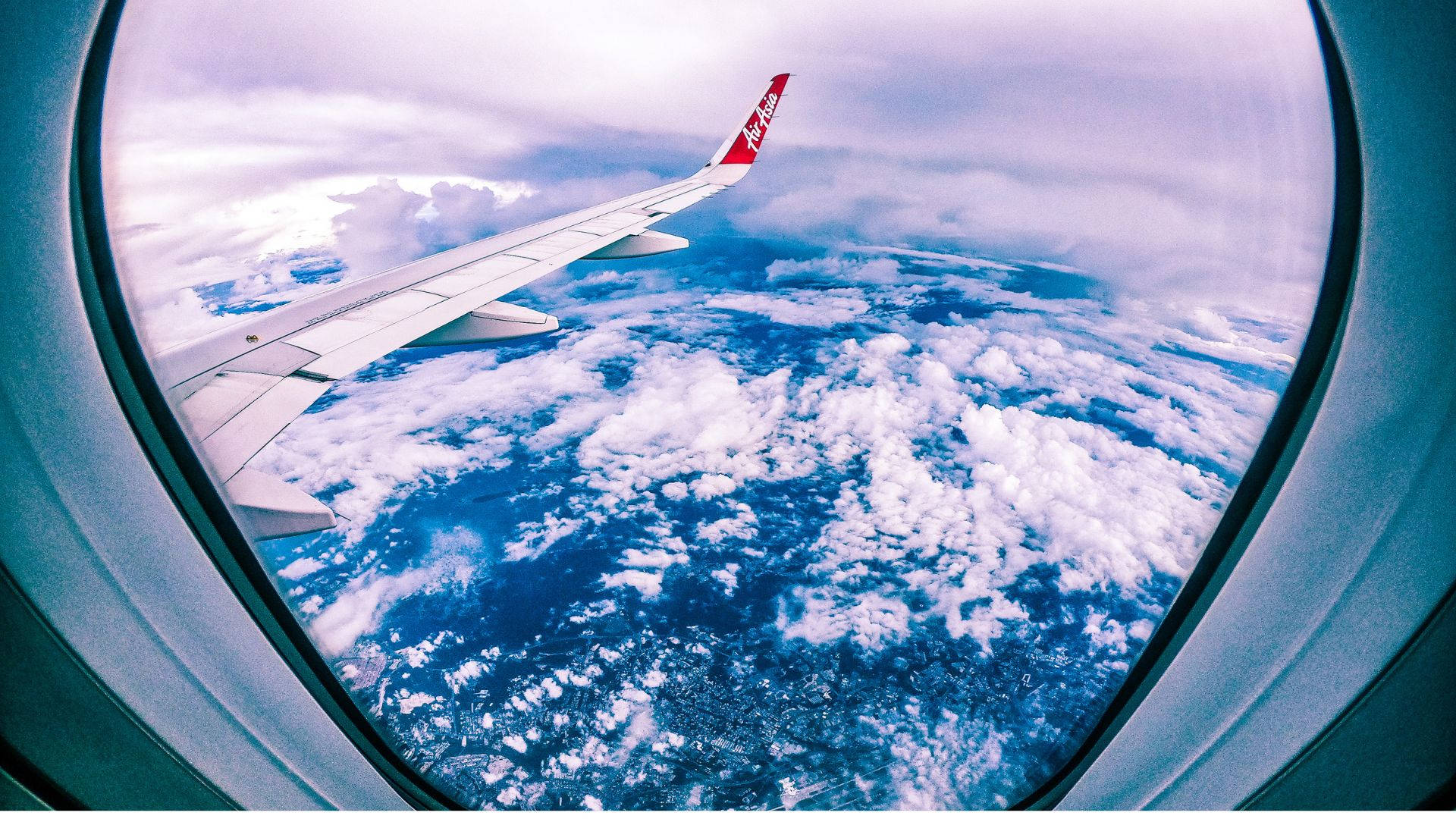 Sky View 桌布 壁紙 — 從飛機窗戶看到的飛機機翼，俯瞰下方蓬鬆的白雲和藍色海洋。