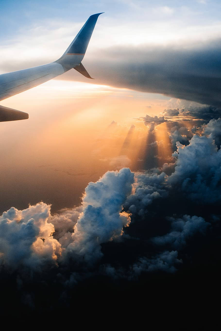 iPhone Travel 桌布 壁紙 — 從飛機窗戶看到陽光穿過雲層，機翼在畫面中。