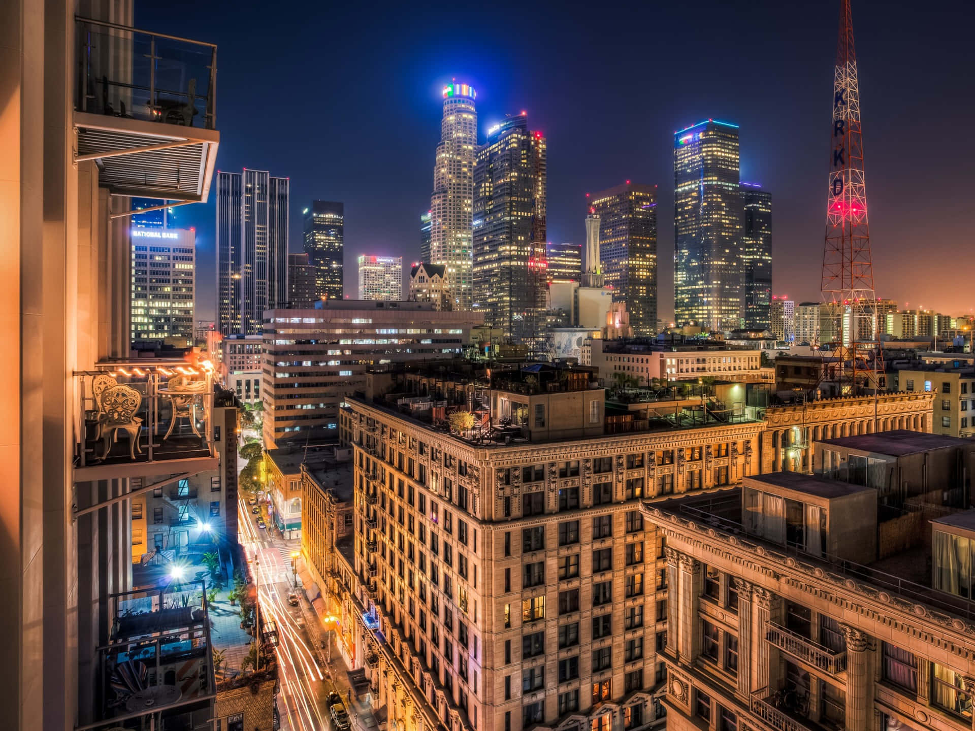 城市 桌布 壁紙 — 從高層陽台觀看的充滿活力的夜景，有明亮的摩天大樓和流動的街燈。