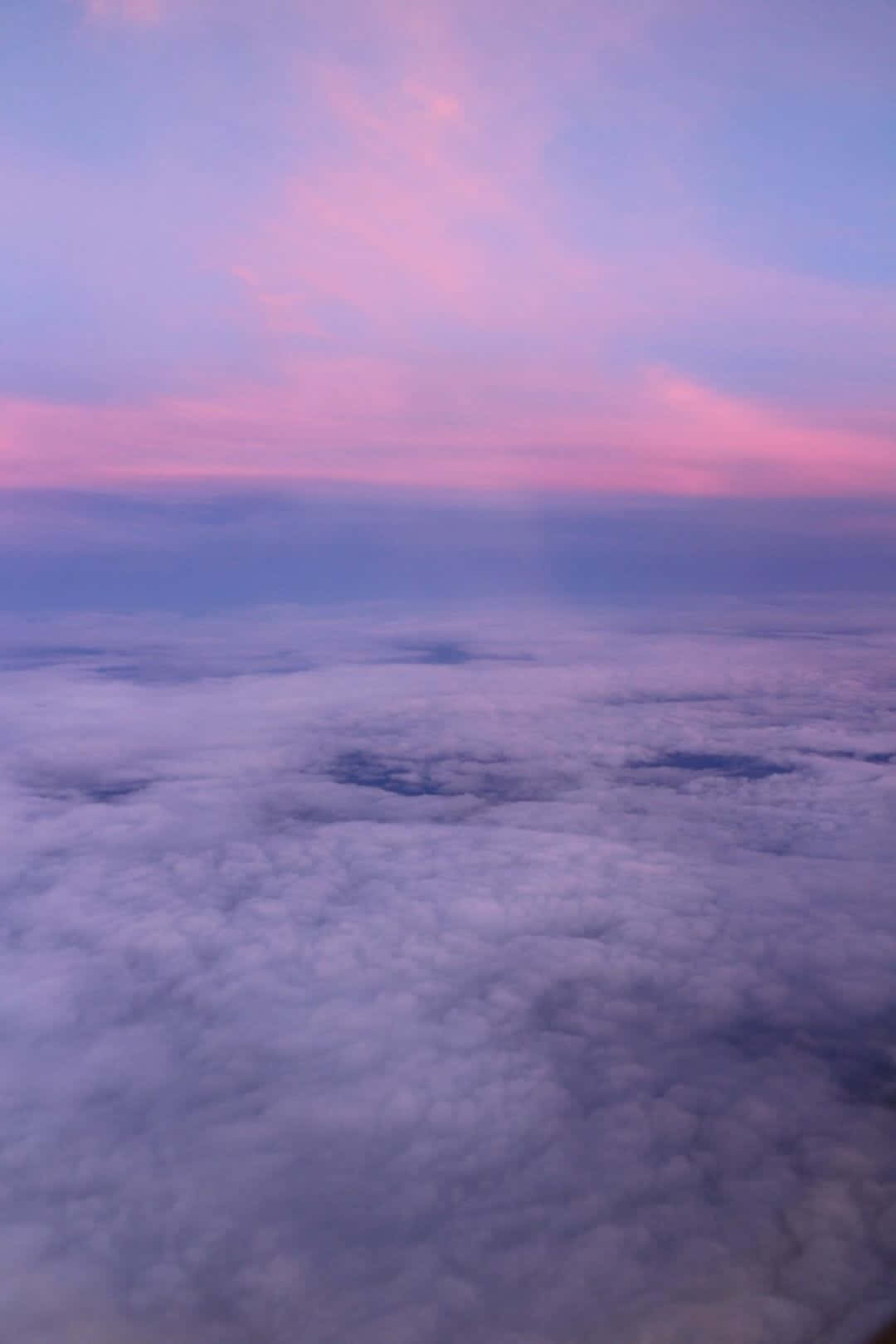 Dope Tumblr iPhone 桌布 壁紙 — 從高空俯瞰， fluffy 雲朵沐浴在柔和粉紅與紫色暮光中的寧靜景象。