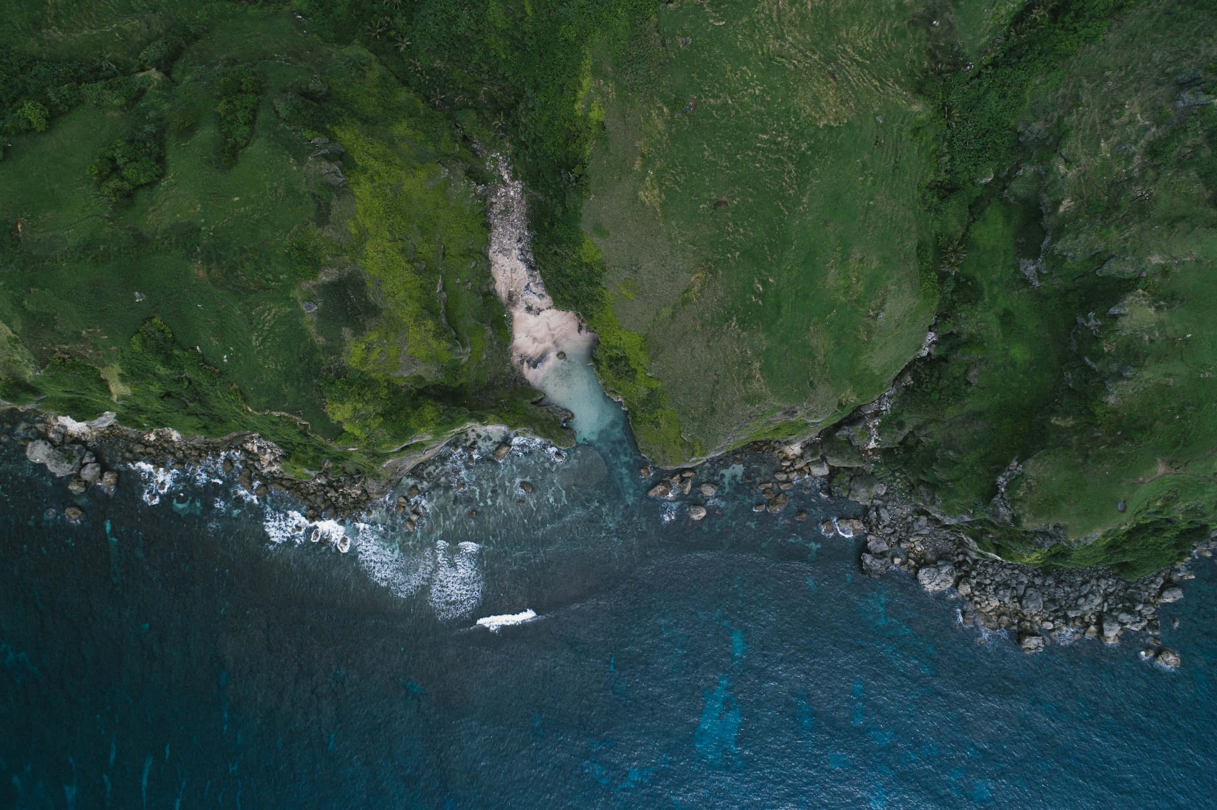 Best Nature 桌布 壁紙 — 從高空俯瞰，一個隱蔽的藍綠色小海灣 nestled 在鬱鬱蔥蔥的綠色懸崖和深藍色海浪之間。