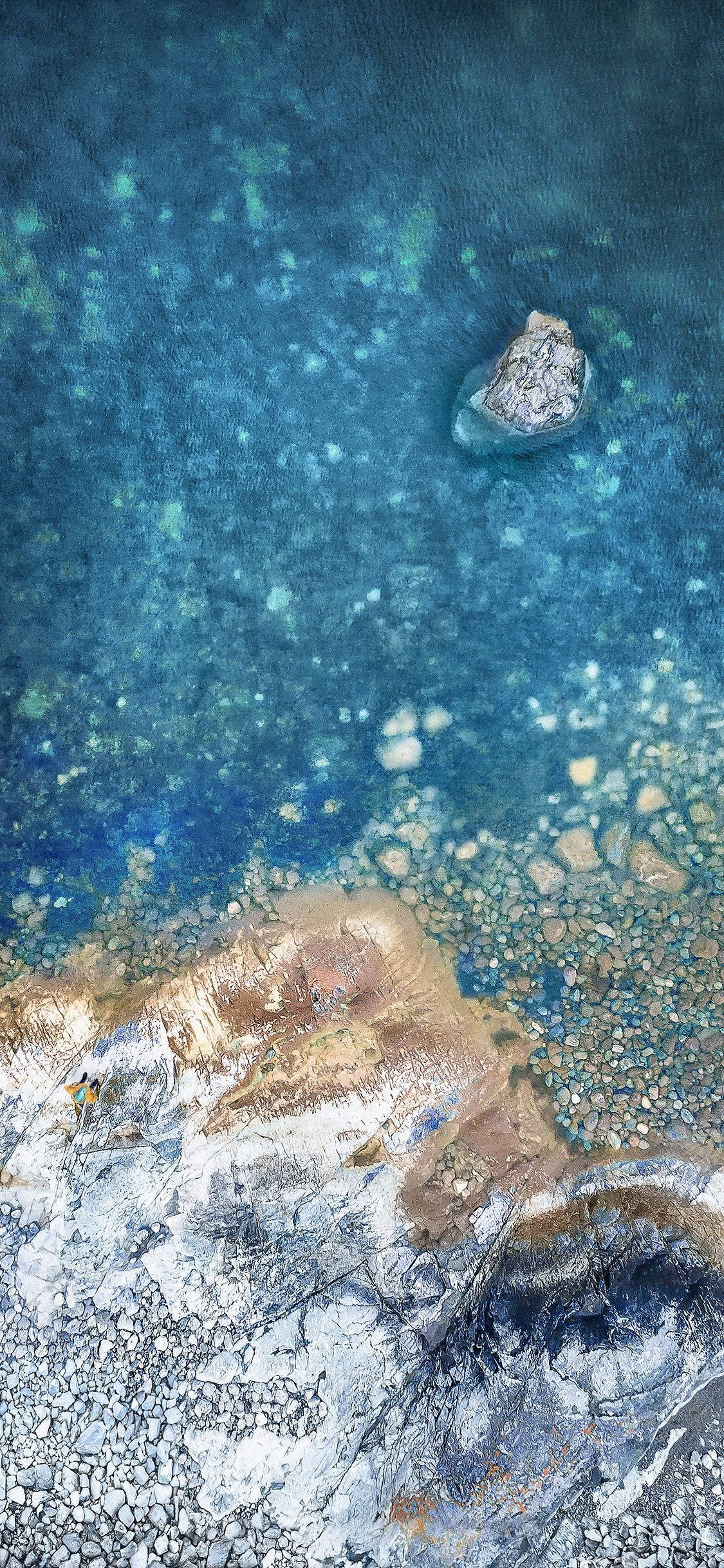 X 桌布 壁紙 — 從高空俯瞰，一塊孤立的岩石被清澈的碧綠海水環繞，下方是紋理分明的沙石海床。