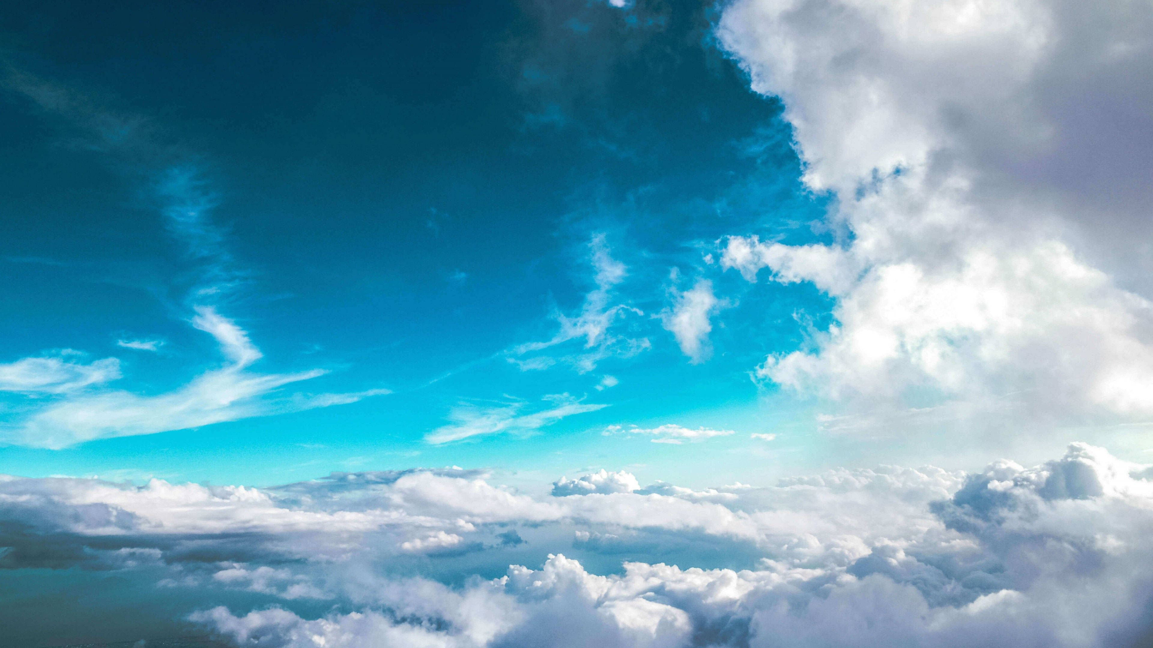 雲朵 桌布 壁紙 — 從高空俯瞰，在廣闊湛藍天空下，翱翔於蓬鬆白雲之上，伴有纖細卷雲的航拍景象。