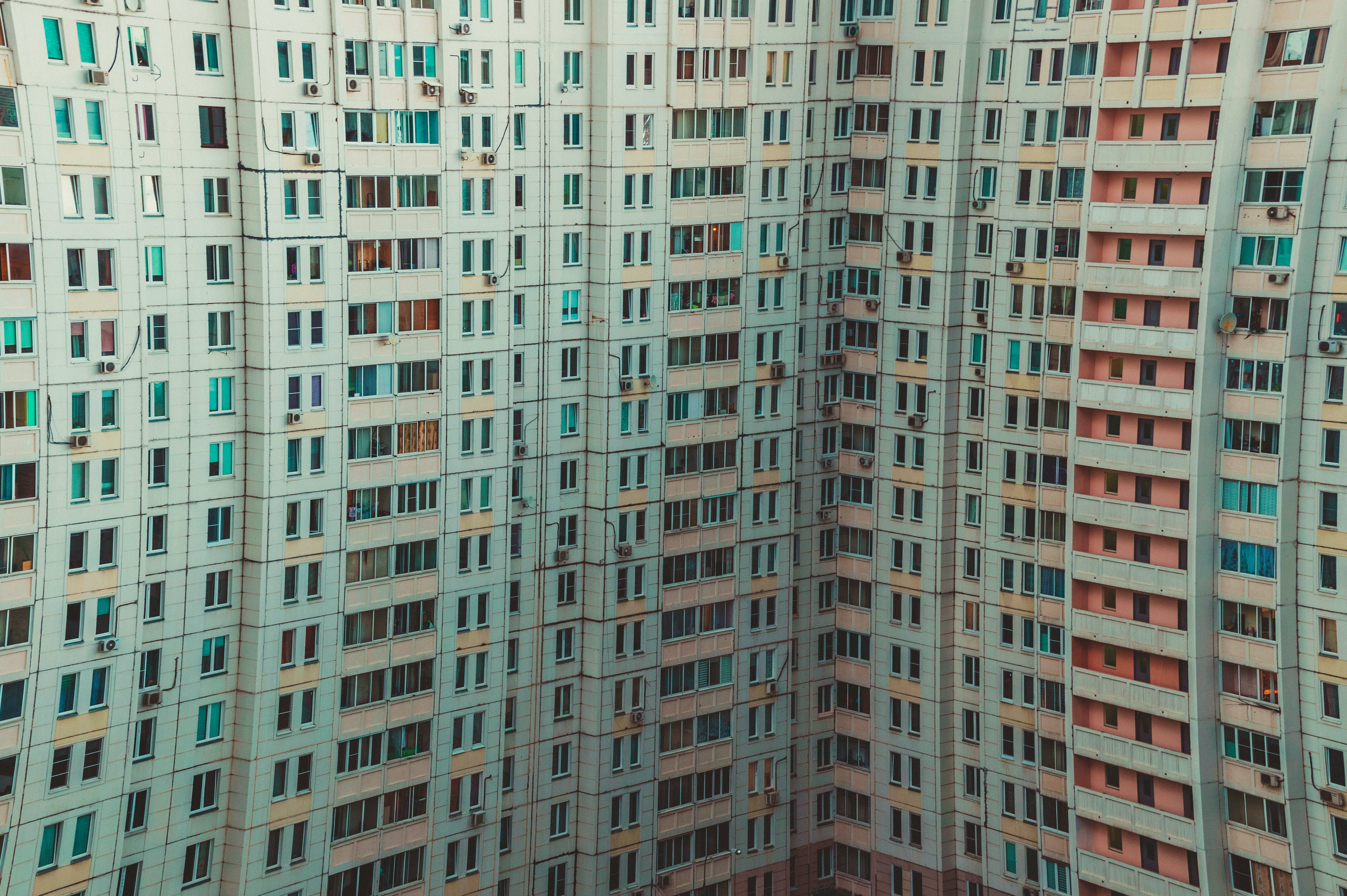 4K HD laptop 桌布 壁紙 — 從高空俯瞰，在柔和日光下，高聳的公寓大樓重複的窗戶和褪色的柔和色調陽台。