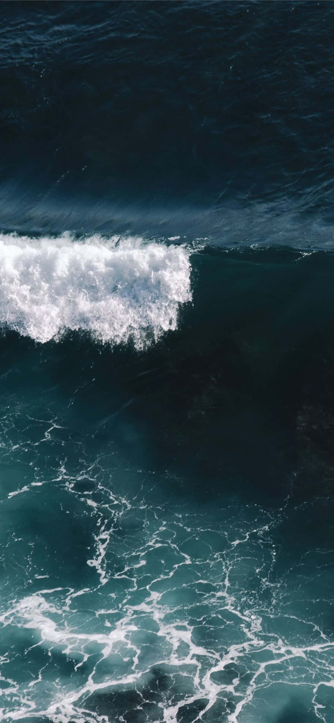 waves 桌布 壁紙 — 從高空俯瞰，巨大的海浪在深藍綠色海面上翻湧，激起白色泡沫。