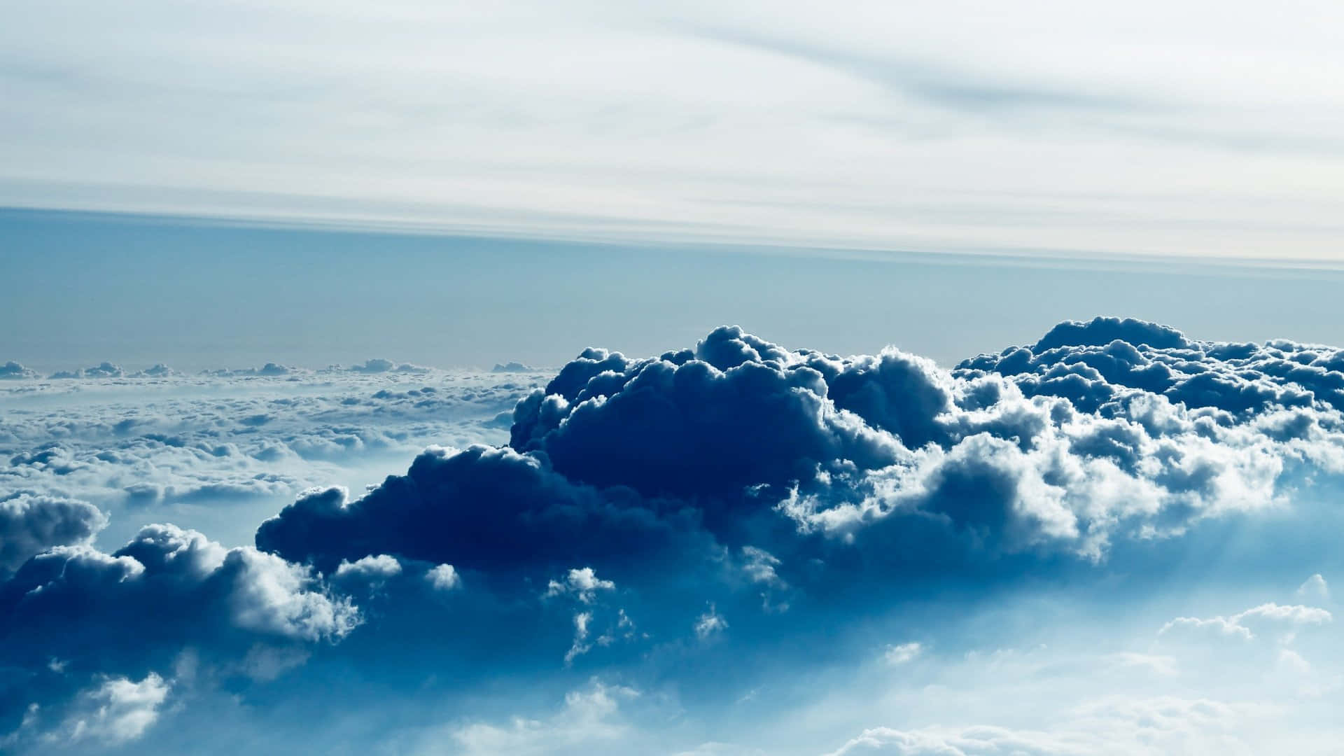 桌布 壁紙 — 從高空俯瞰，戲劇性的藍白雲彩在寧靜的天空中延伸，柔和陽光穿透而過。