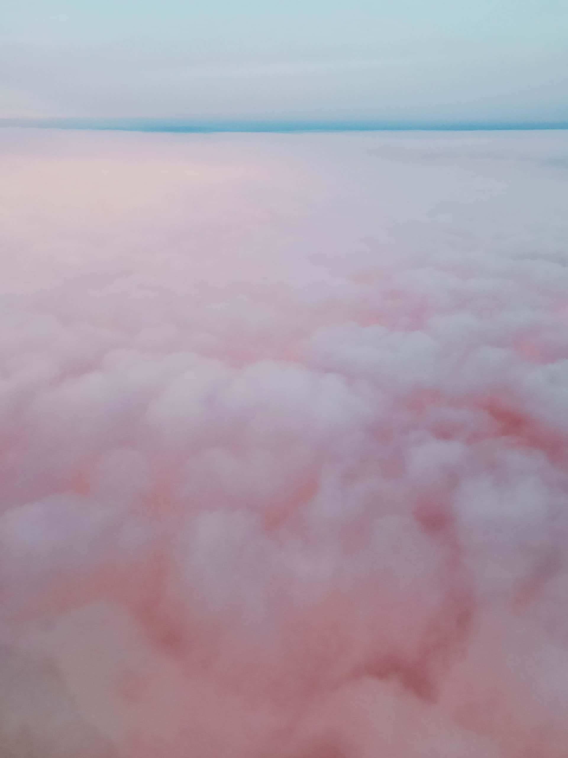 Pink And Blue Clouds 桌布 壁紙 — 從高空俯瞰，柔和的粉紅色和白色雲朵在淡藍色天空下延伸至地平線。