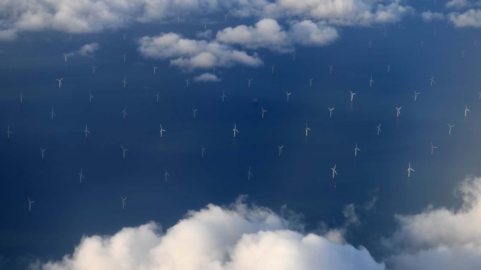 Wind 桌布 壁紙 — 從高空俯瞰，無數風力發電機點綴在深藍色的天空中，散落著蓬鬆的白雲。