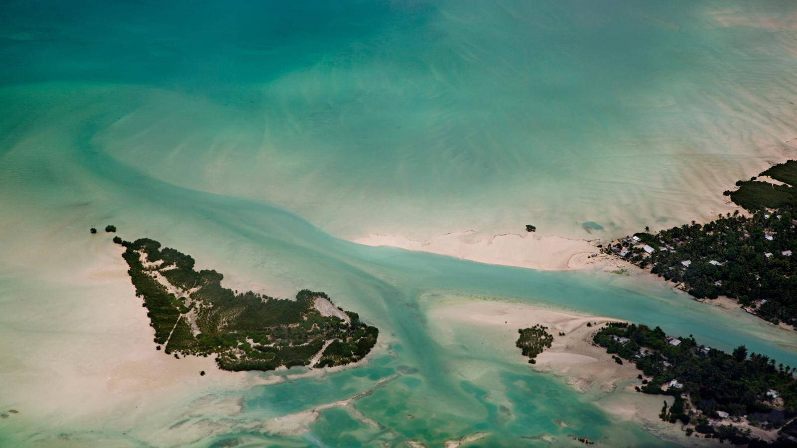 Kiribati 桌布 壁紙 — 從高空俯瞰，碧綠的海水圍繞著沙質小島和茂密的綠色植被，零星分佈著建築物。