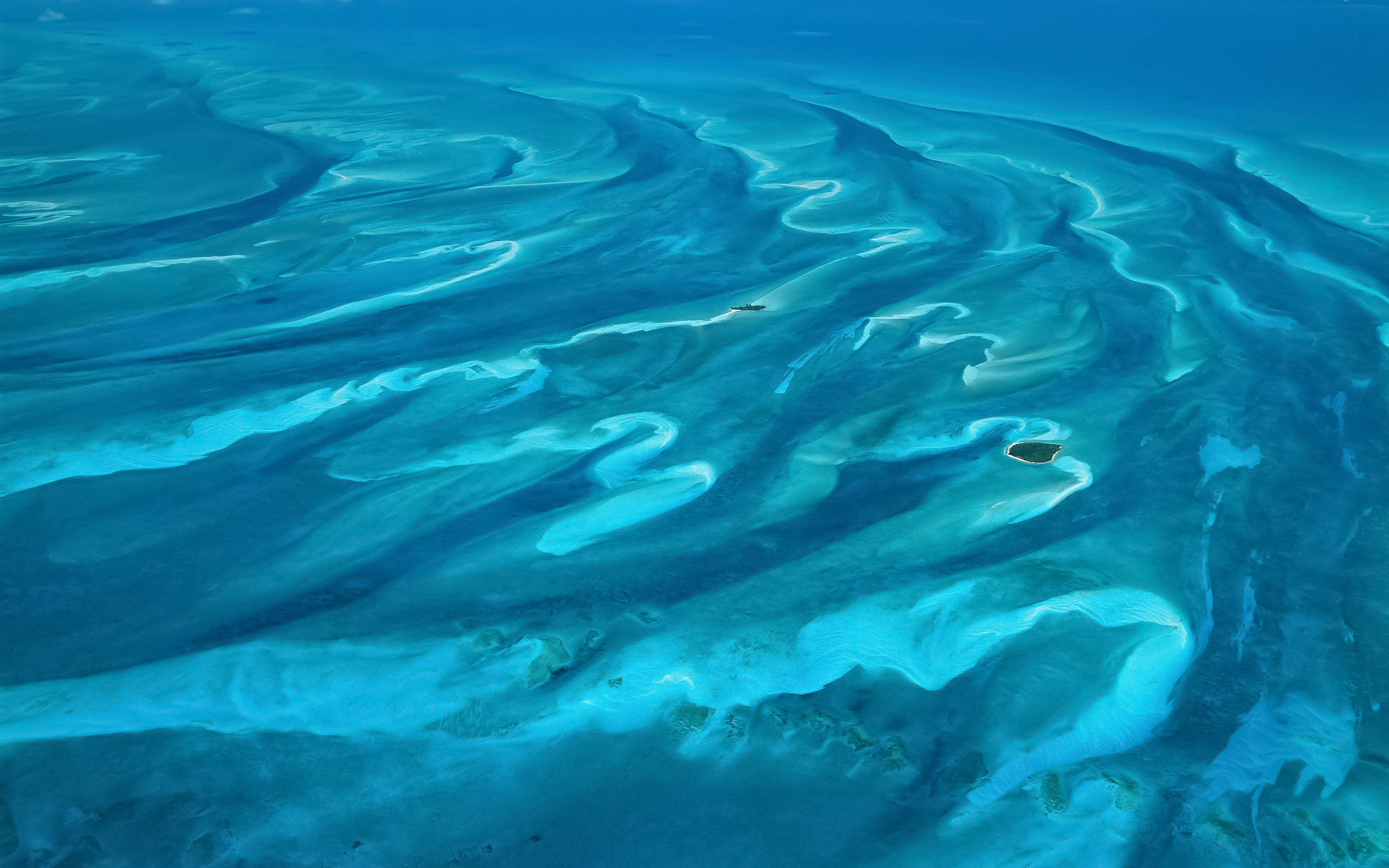 背景 桌布 壁紙 — 從高空俯瞰，碧綠的海水在沙洲和小島周圍旋轉，呈現出充滿活力的藍色海洋。
