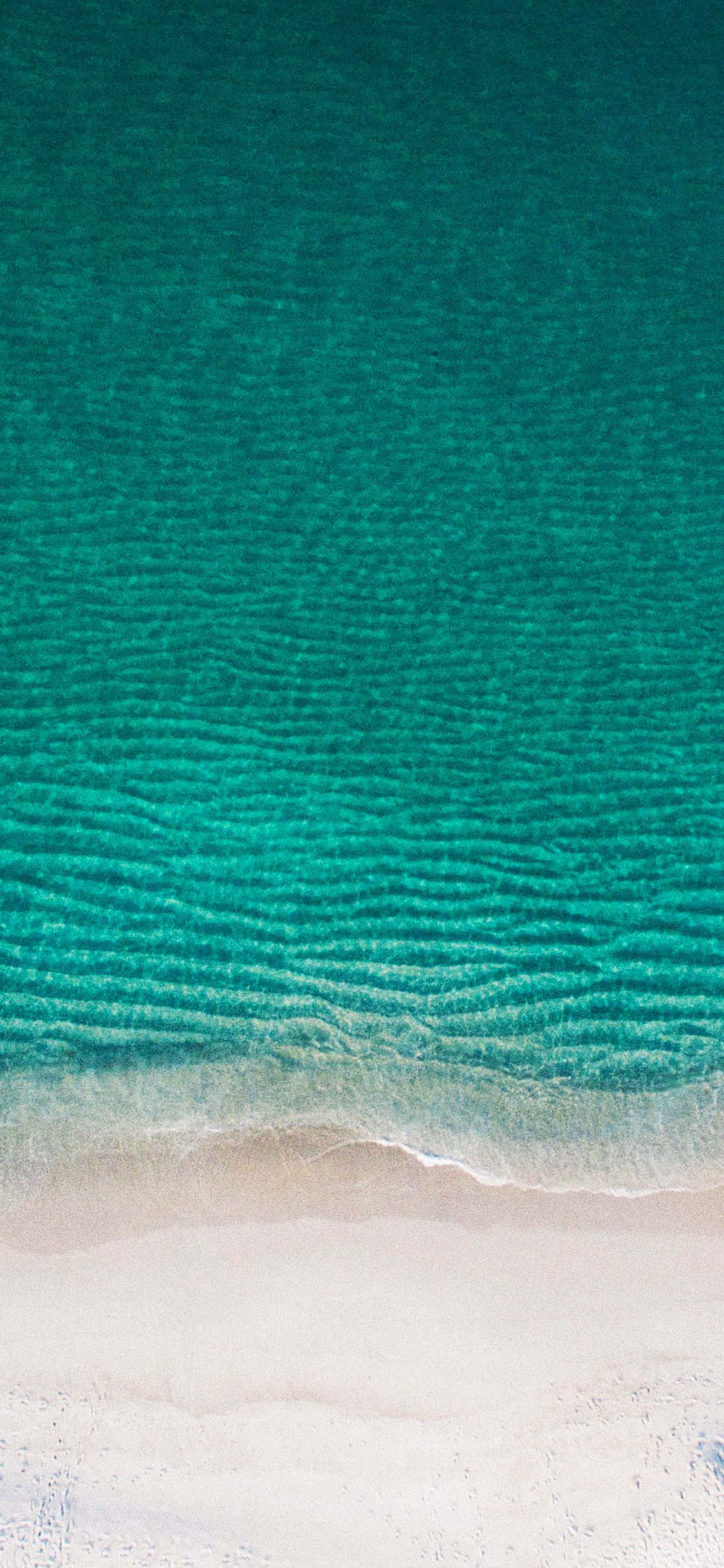 iPhone X Nature 桌布 壁紙 — 從高空俯瞰，碧綠的海浪輕輕拍打著純淨的白色沙灘。