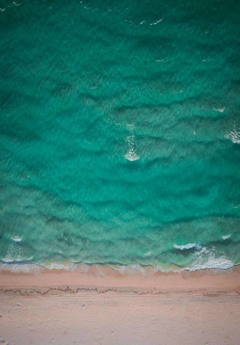 海灘 桌布 壁紙 — 從高空俯瞰，碧綠的海浪輕輕拍打著淡粉色的沙灘。