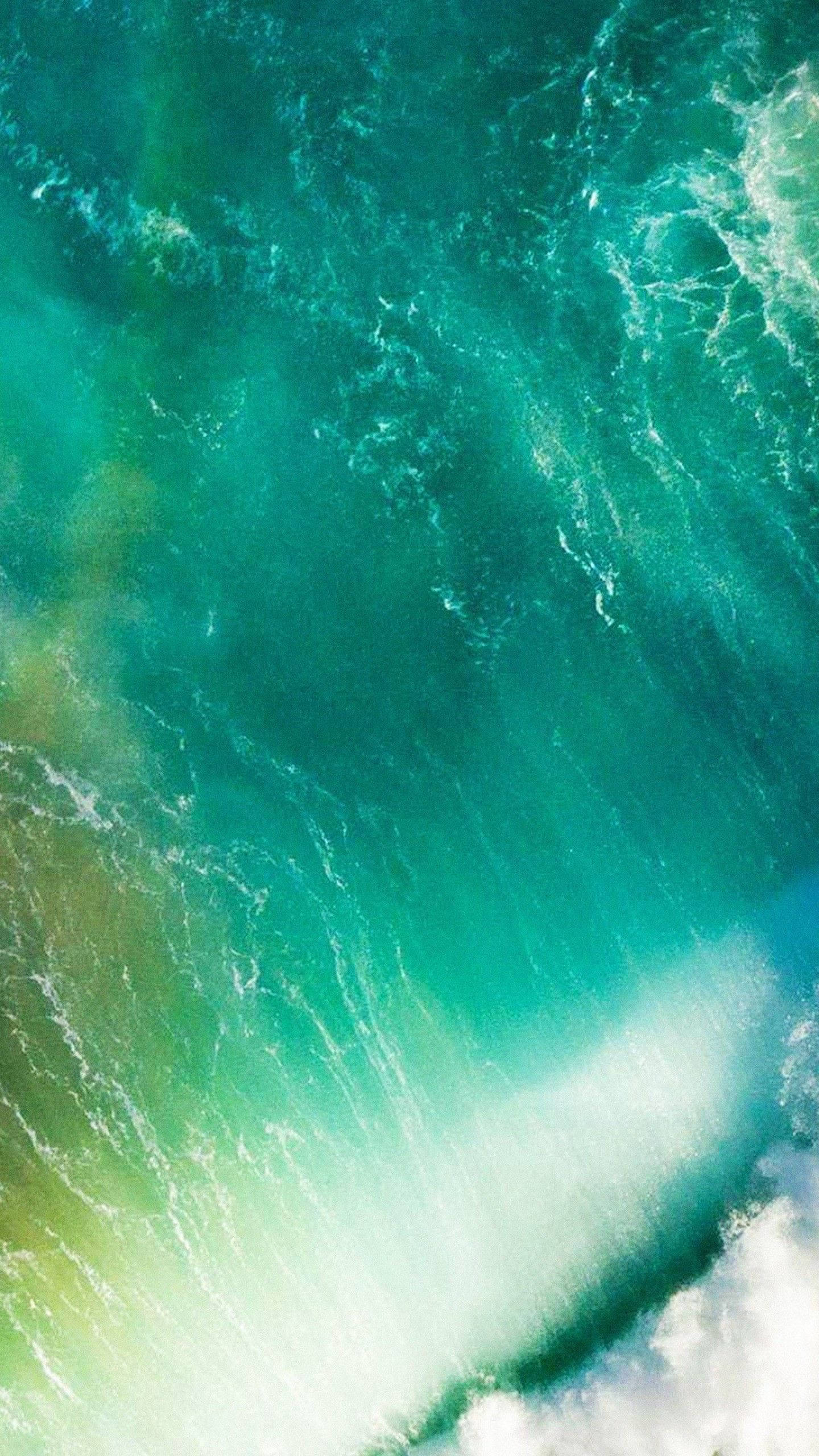 Apple iPhone 預設 桌布 壁紙 — 從高空俯瞰，碧綠色的海浪拍打岩石海岸，激起白色泡沫。