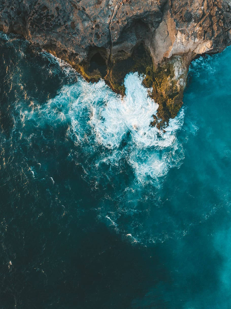 Wave 桌布 壁紙 — 從高空俯瞰，碧綠色的海浪拍打著崎嶇的黑色懸崖，激起白色泡沫。