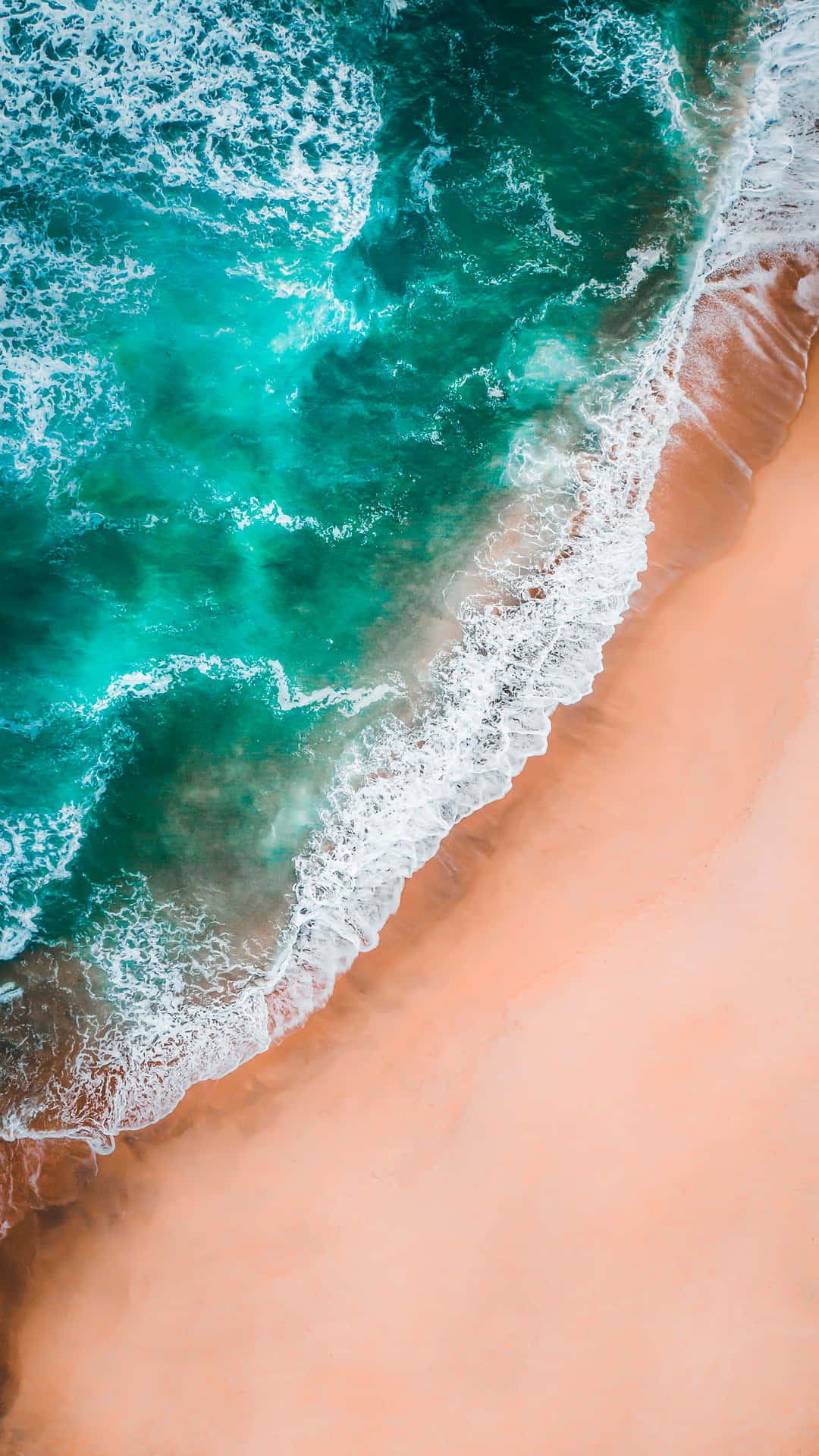 Pretty Ocean 桌布 壁紙 — 從高空俯瞰，碧綠色的海浪拍打著柔軟的蜜桃色沙灘，形成鮮明對比。