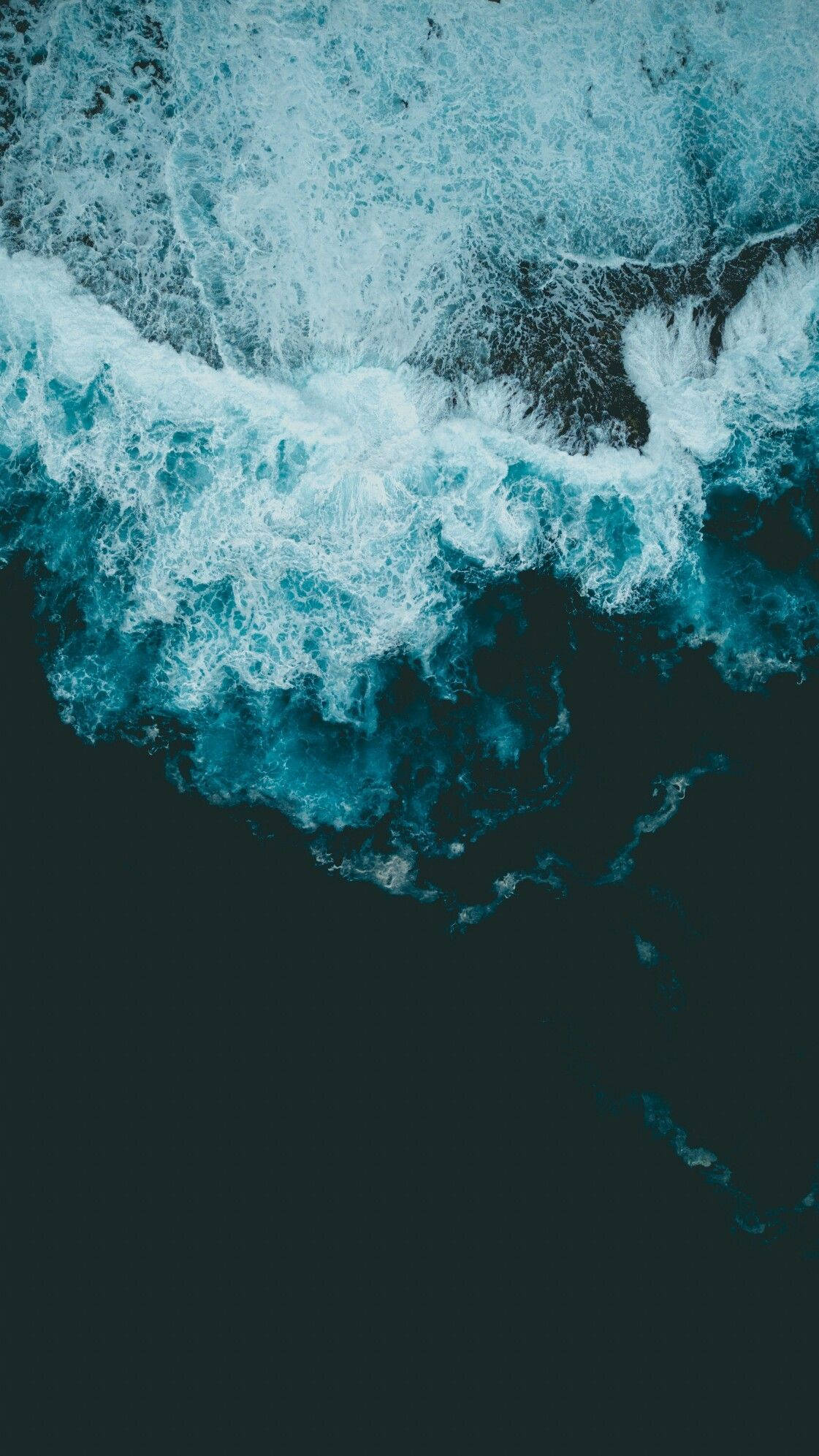 Cool Android 桌布 壁紙 — 從高空俯瞰，碧綠色的海浪拍打著黑暗的海岸，激起白色泡沫般的浪花。