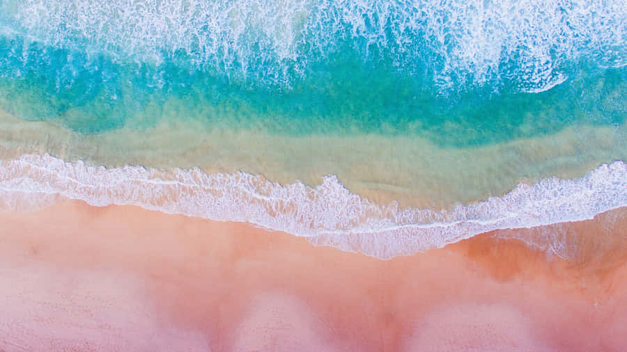 Pink Beach 桌布 壁紙 — 從高空俯瞰，綠松石色的海浪拍打著柔軟的粉紅色沙灘，邊緣泛起白色泡沫。