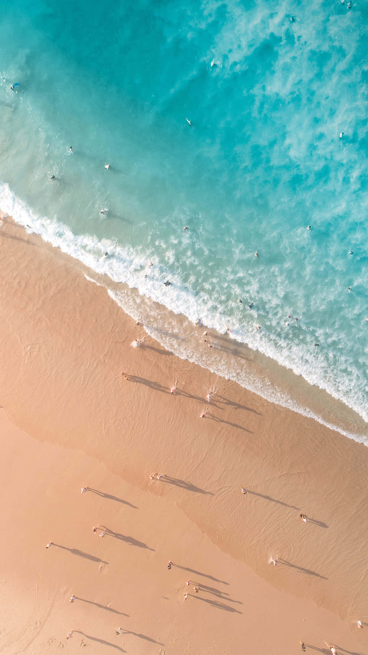 Beach Holiday 桌布 壁紙 — 從高空俯瞰，綠松石色的海浪拍打著金色沙灘，散落的遊客投下長長的影子。