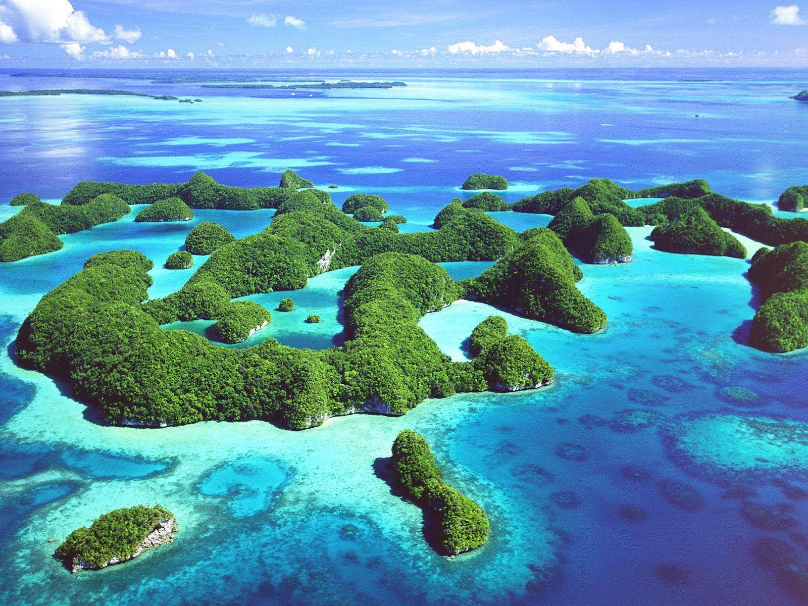 Palau 桌布 壁紙 — 從高空俯瞰，翠綠島嶼散落在鮮豔的藍綠色和深藍色水域中，天空明亮。