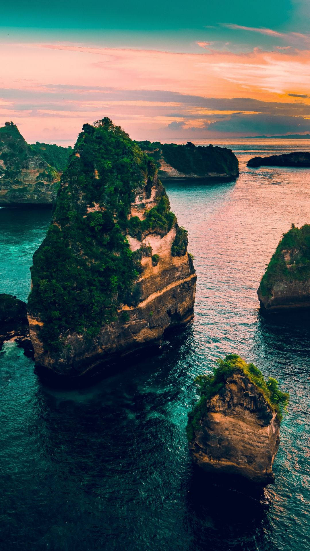 印尼 桌布 壁紙 — 從高空俯瞰，翠綠的海蝕柱從深藍色海水中聳立，映襯著色彩斑斕的日落天空。