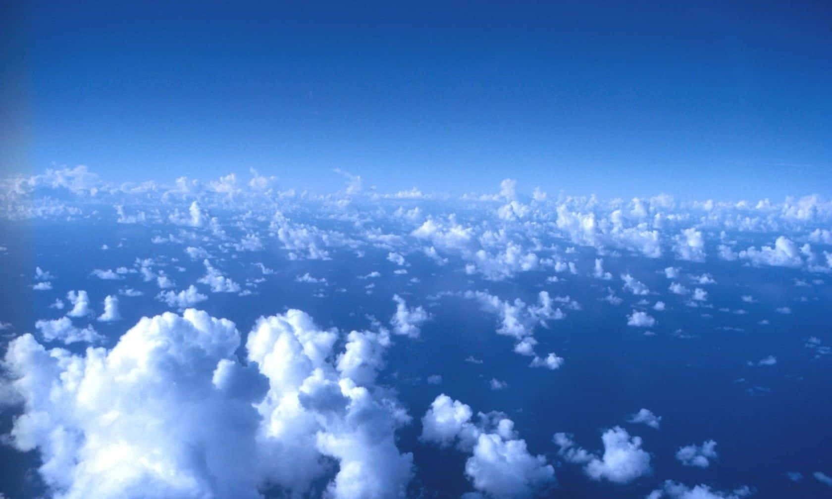 Weather 桌布 壁紙 — 從高空俯瞰，蓬鬆的白雲漂浮在深藍色天空上的航拍圖。