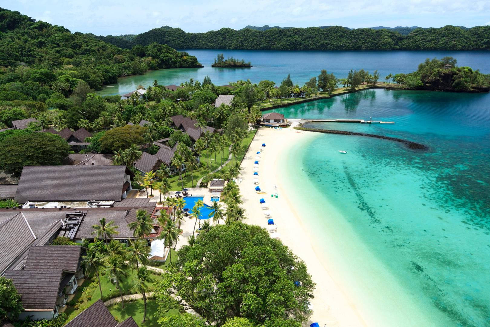 Micronesia 桌布 壁紙 — 從高空俯瞰，豪華度假村坐落在純淨的白色沙灘上，背景是碧綠的海水和鬱鬱蔥蔥的綠色山丘。