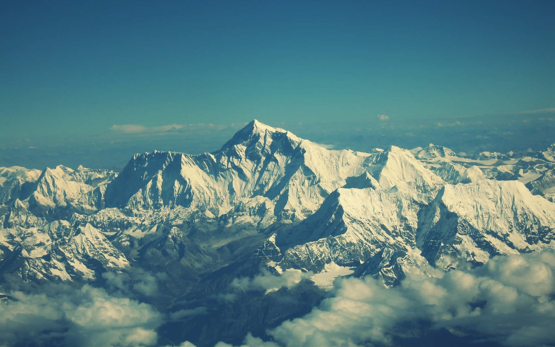 Himalaya 桌布 壁紙 — 從高空俯瞰，雄偉的雪山峰頂在清澈藍天下穿過雲層。