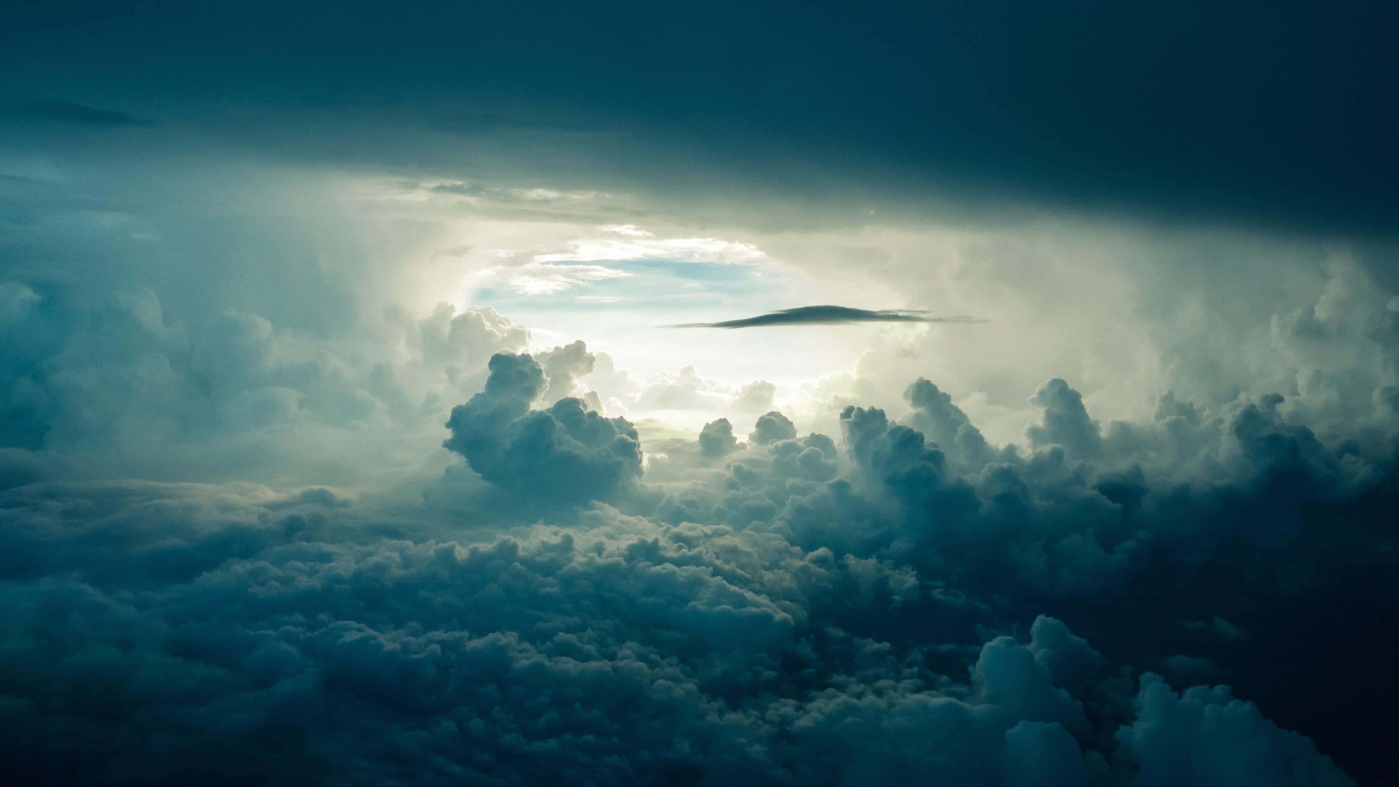 Clouds Aesthetics 桌布 壁紙 — 從高空俯瞰，高聳的雲層被穿透黑暗暴風雨天空的陽光照射，形成戲劇性的景象。