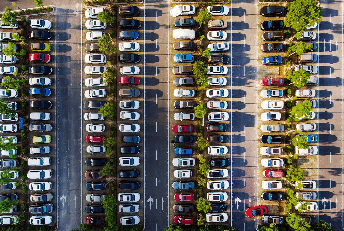 汽車 桌布 壁紙 — 從高空俯瞰一個大型停車場，在明亮陽光下，色彩繽紛的汽車整齊排列成行。