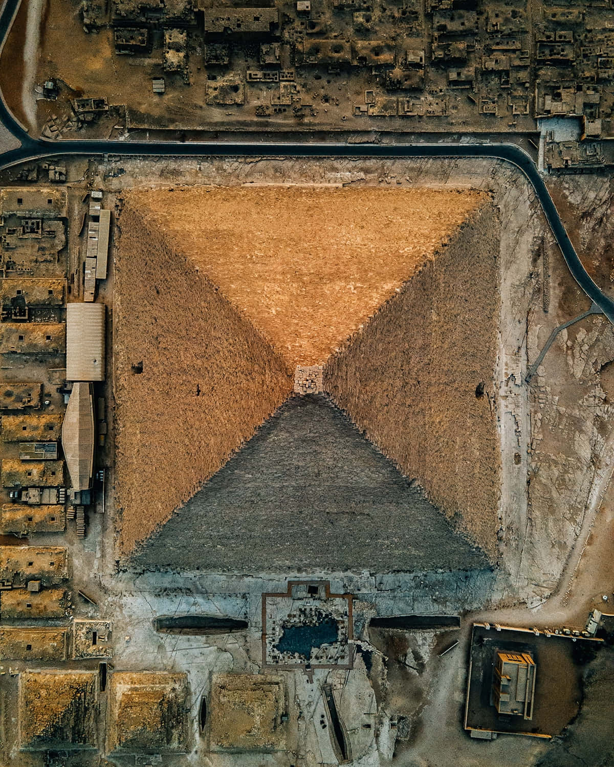 Aerial 桌布 壁紙 — 從高空俯瞰一座巨大的古老金字塔，石塊風化，周圍是沙漠廢墟，在明亮的日光下。