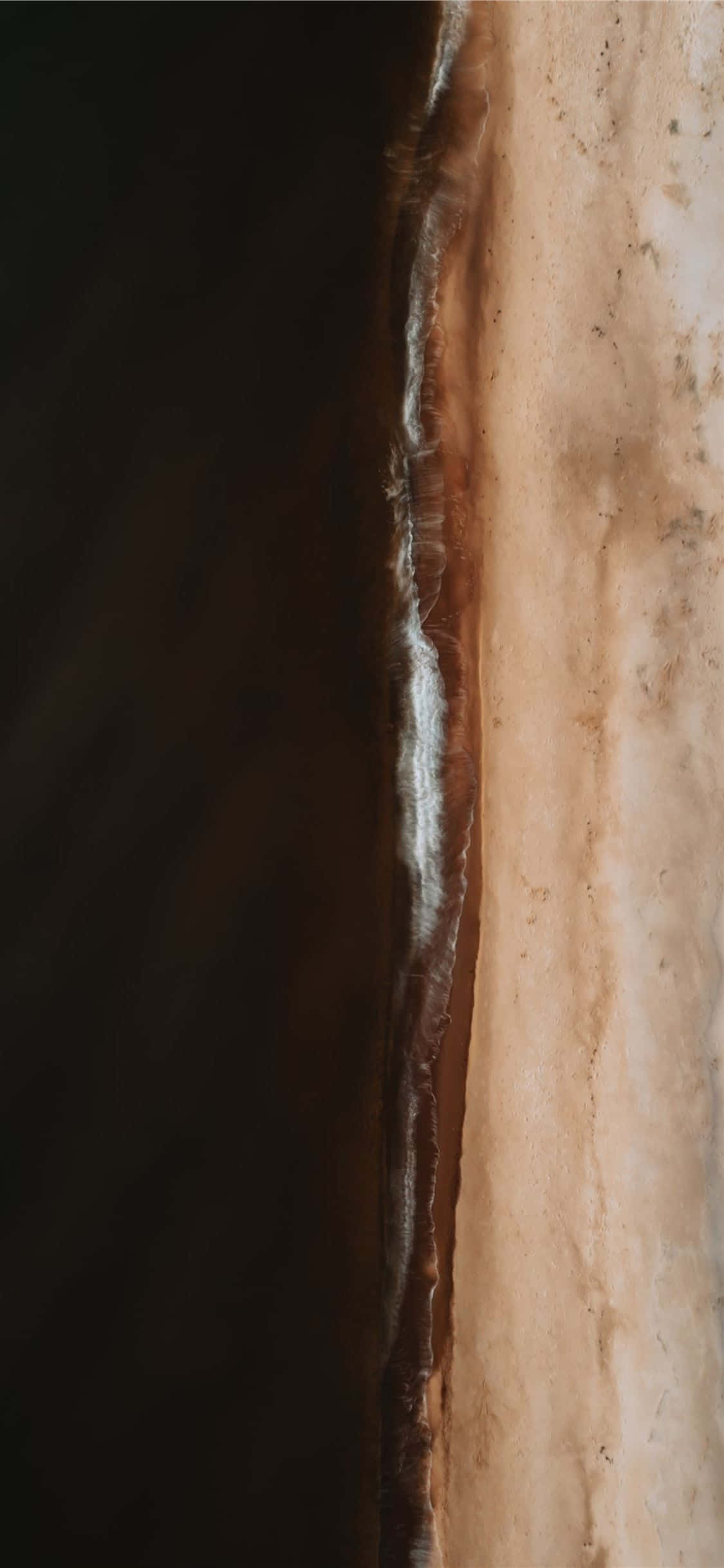Brown And White 桌布 壁紙 — 從高空俯瞰一條清晰的海岸線，深色海水與淺色沙灘形成戲劇性的垂直分割。