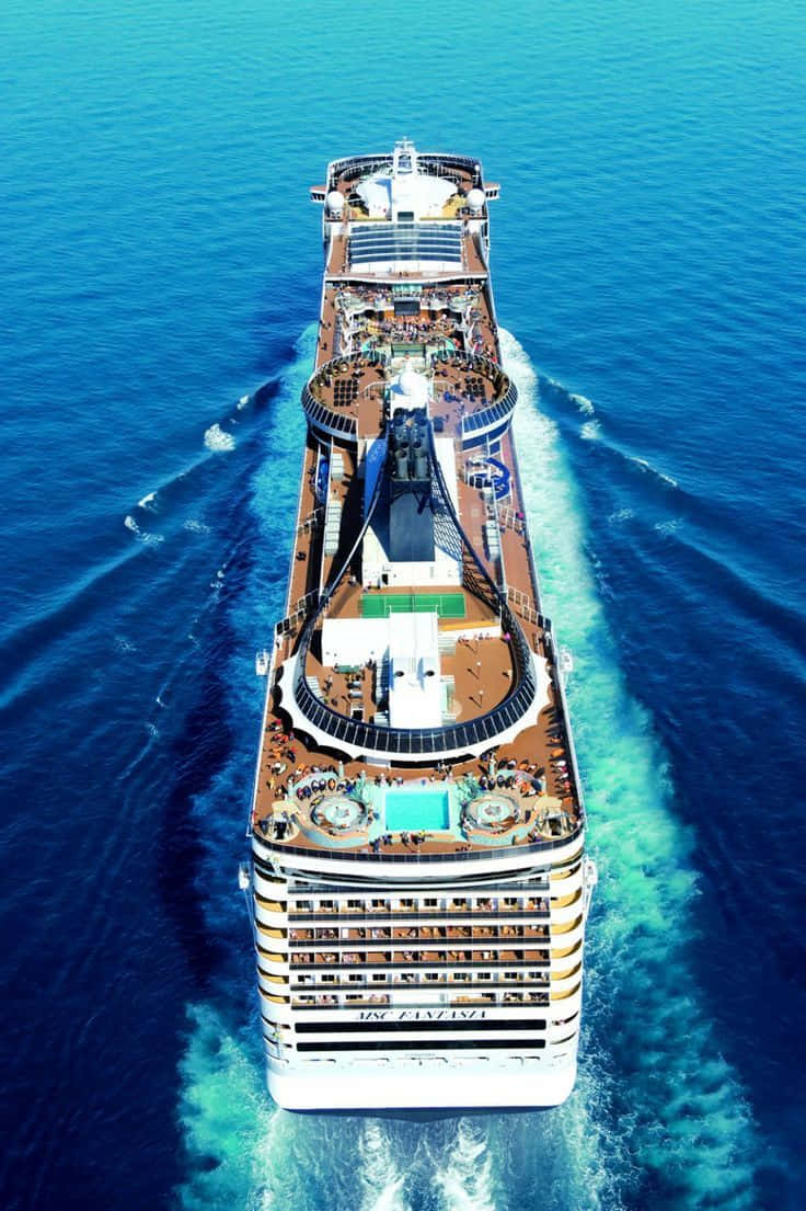 Cruise 桌布 壁紙 — 從高空俯瞰一艘巨型郵輪劃破深藍色海水，留下白色泡沫尾跡。