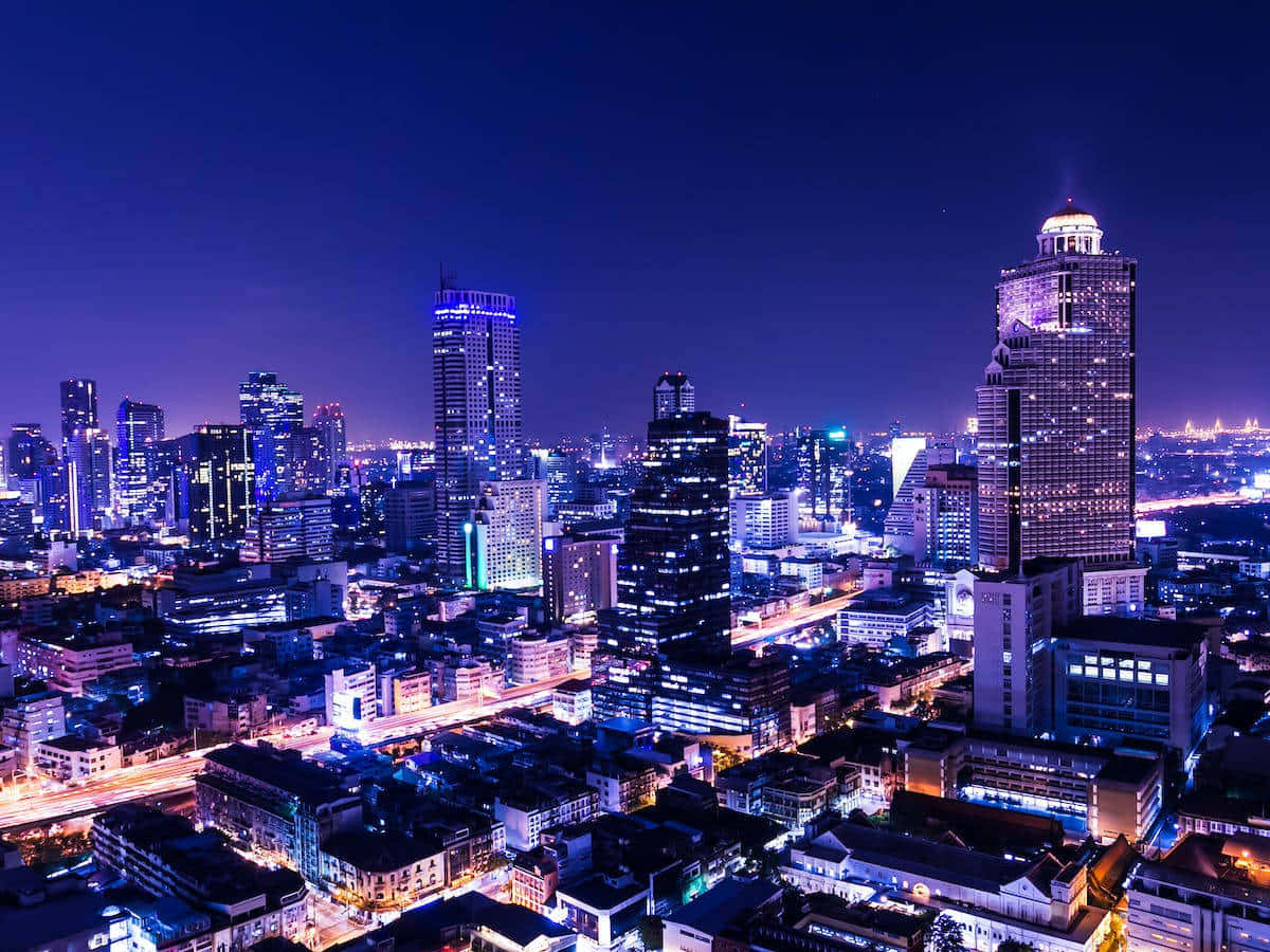 City Night 桌布 壁紙 — 從高空俯瞰充滿活力的城市夜景，高聳的摩天大樓在深藍色天空下閃耀。