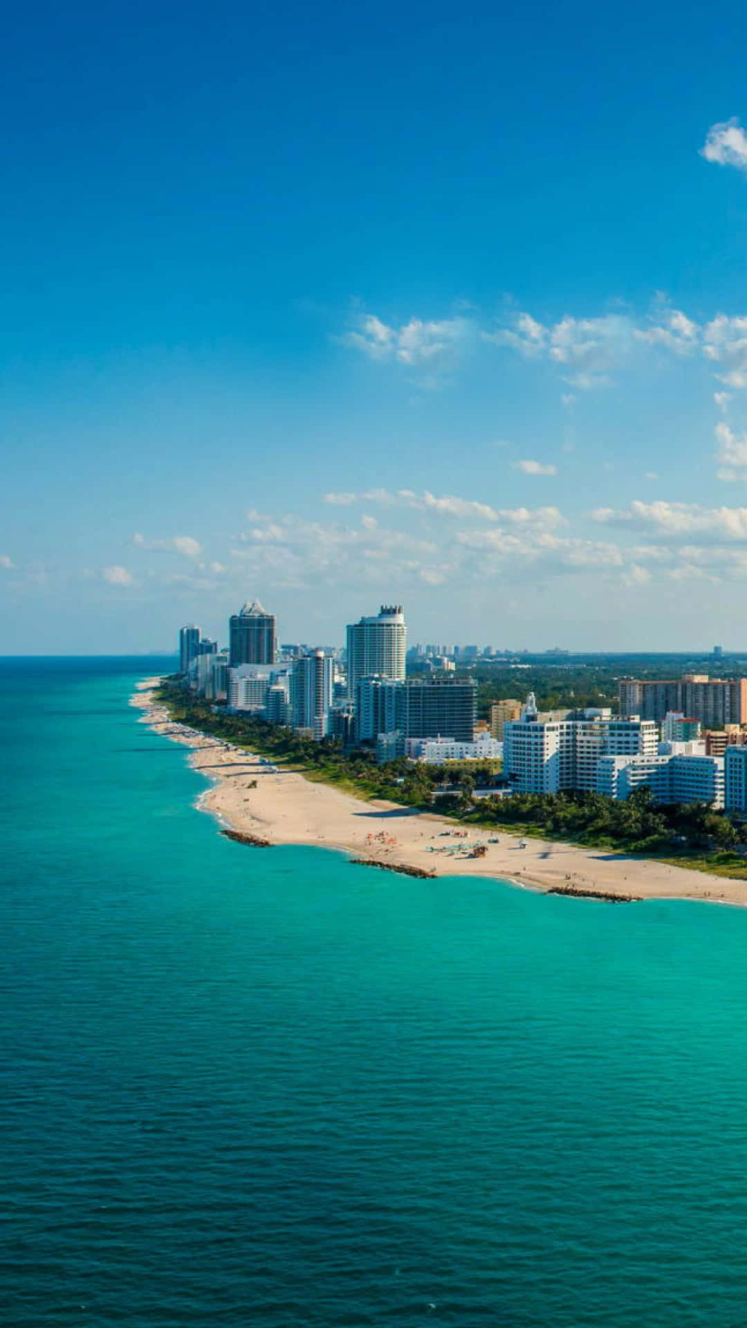 Miami iPhone 桌布 壁紙 — 從高空俯瞰充滿活力的沿海城市，碧綠的海洋、沙灘和現代高層建築在晴朗的藍天下。