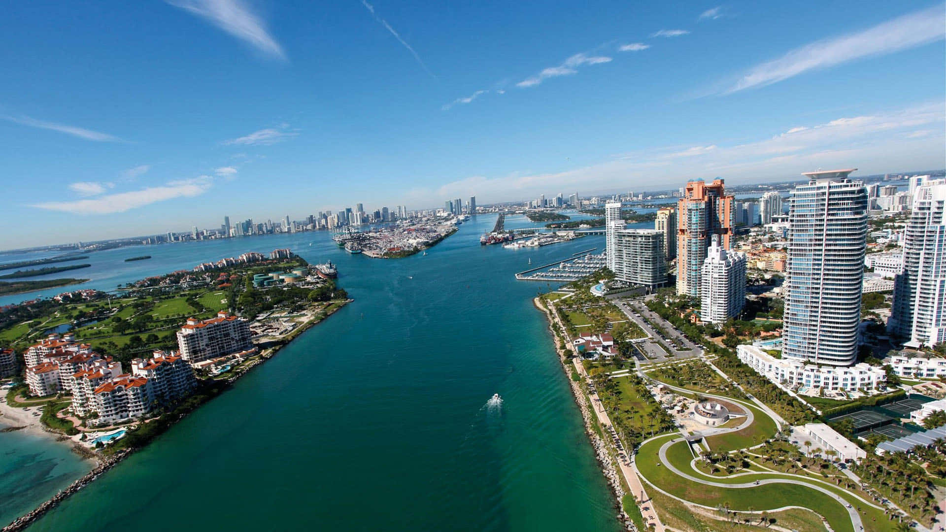 Miami 桌布 壁紙 — 從高空俯瞰充滿活力的沿海城市，碧綠的海水兩旁是現代化的摩天大樓和鬱鬱蔥蔥的公園，天空清澈湛藍。