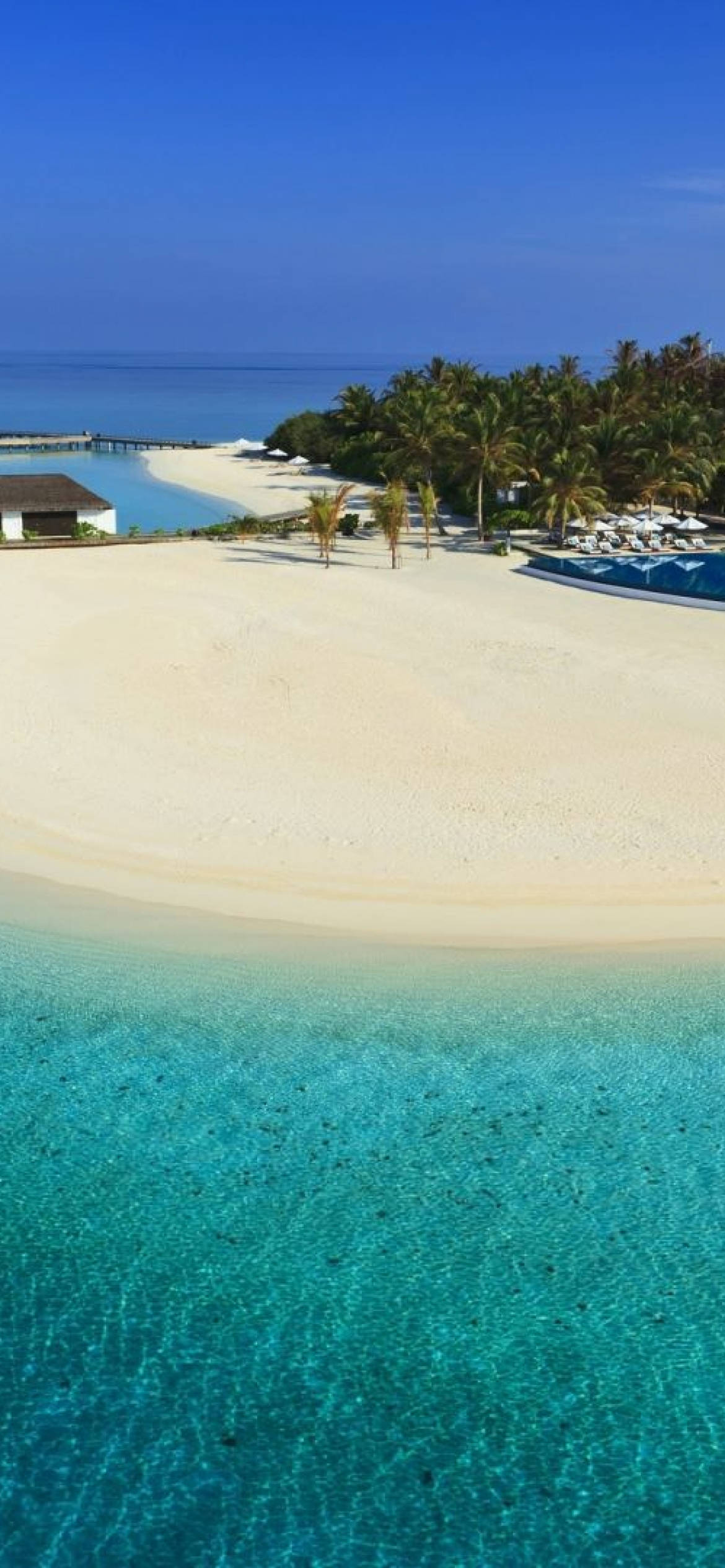 Nassau Bahamas 桌布 壁紙 — 從高空俯瞰原始熱帶海灘，擁有碧綠海水、白色沙灘、棕櫚樹和度假村設施，天空清澈湛藍。