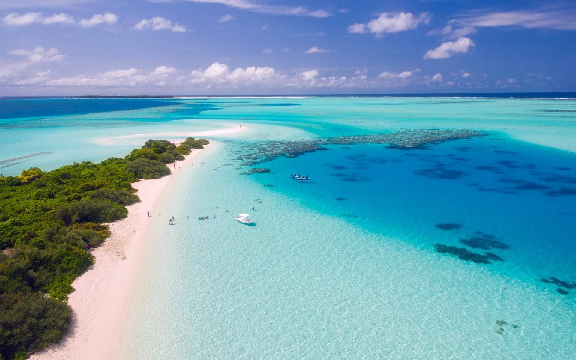 White Beach 桌布 壁紙 — 從高空俯瞰原始熱帶環礁，擁有碧綠色的潟湖、珊瑚礁和白色沙灘，在明亮的藍天下。