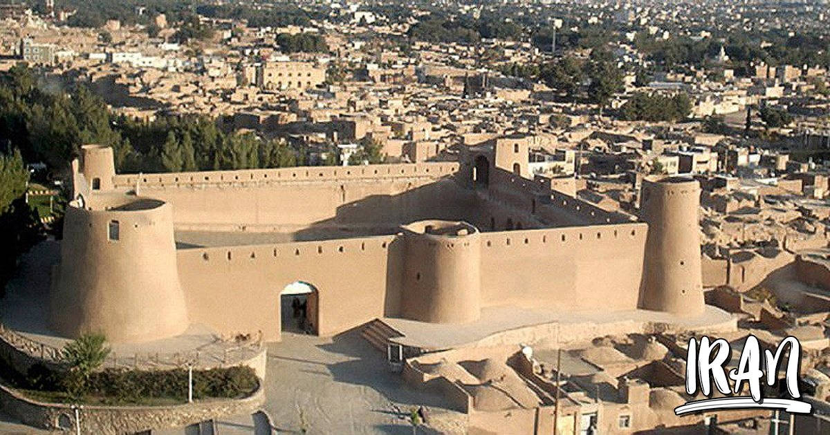 Iran 桌布 壁紙 — 從高空俯瞰古老的泥磚堡壘塔樓，俯瞰沐浴在金色陽光下的廣闊伊朗城市景觀。