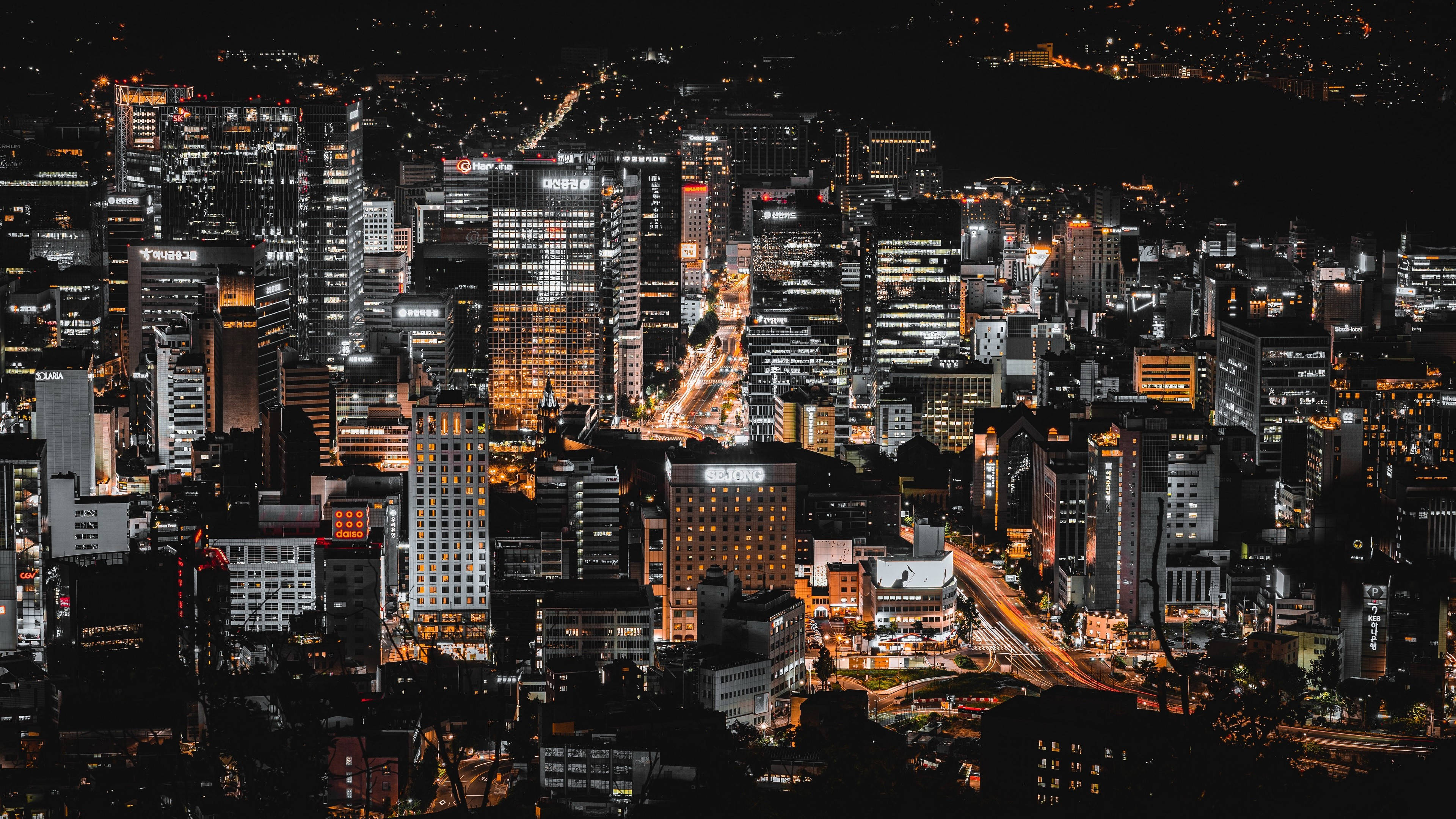 Asia 桌布 壁紙 — 從高空俯瞰夜晚中燈火通明的摩天大樓與車流燈光交織的廣闊城市景觀。