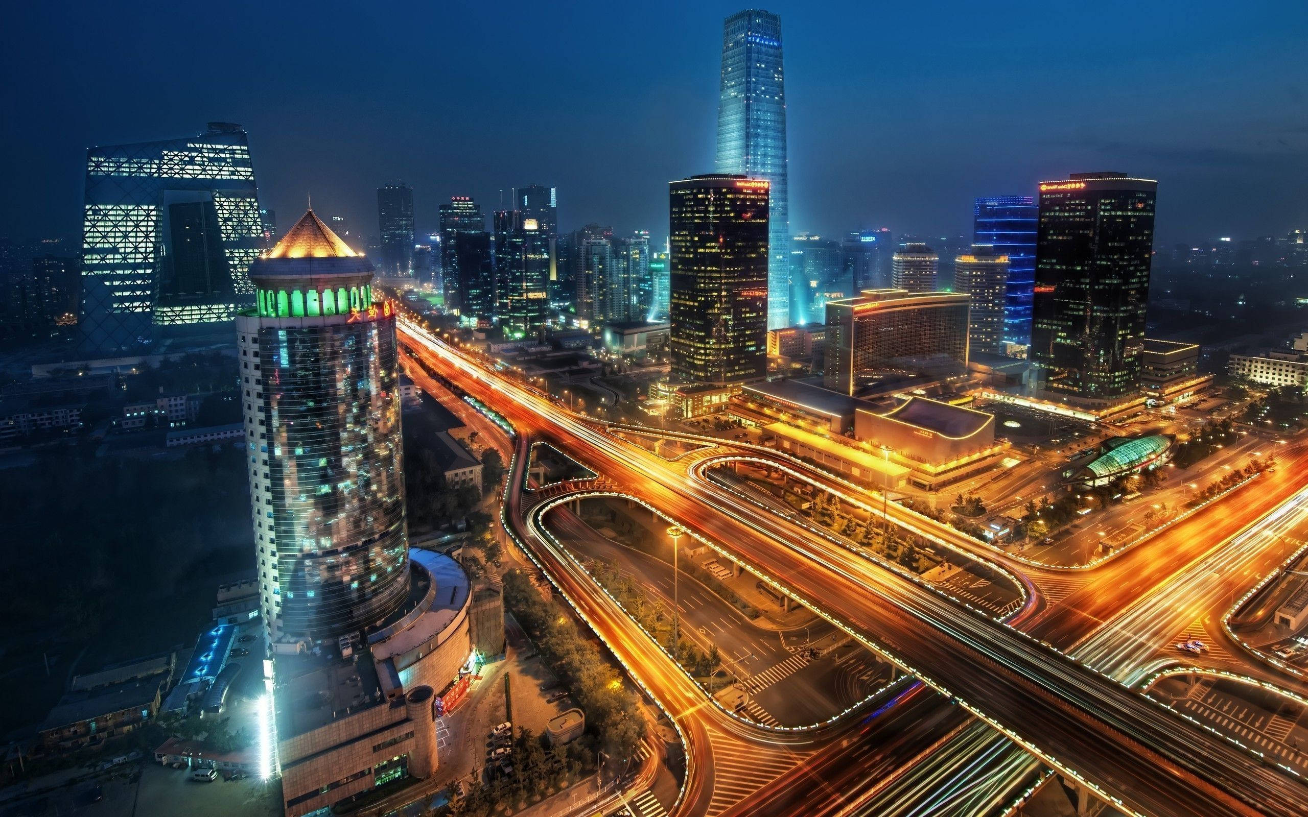 Tianjin 桌布 壁紙 — 從高空俯瞰夜晚充滿活力的城市，閃爍的摩天大樓和蜿蜒高速公路上流動的車燈光軌。