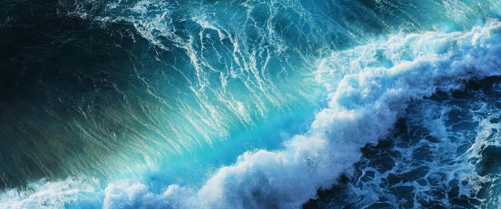 強勁的海浪撞擊著深藍色海水，泛起藍綠色泡沫。 — 超寬 GIF 壁紙